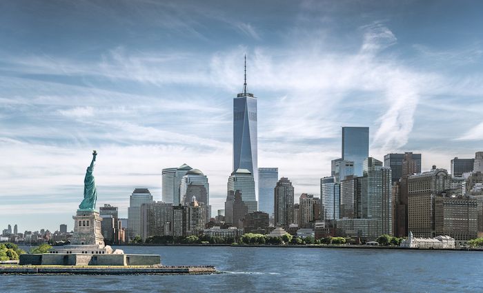 NYC skyline with One World Trade Center. In the foreground, statue of Liberty. How to visit ground zero and 911 memorial